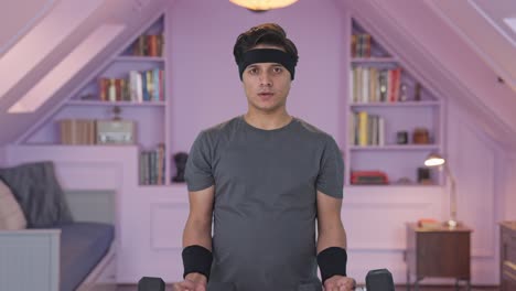 인도인 남자가 무거운 덤벨을 들어 올리고 운동을 하고 있습니다.