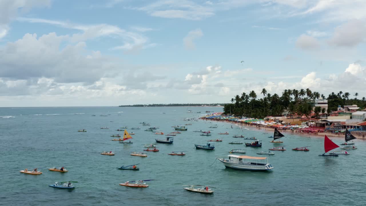 dron aéreo con plataforma rodante toma amplia de la playa de porto de galinhas o puerto de pollo con veleros anclados, un ala delta y turistas nadando en las aguas cristalinas del océano en pernambuco, brasil