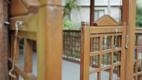 old wooden entrance gate swinging back and forth violently after someone walked out of home in slowmo