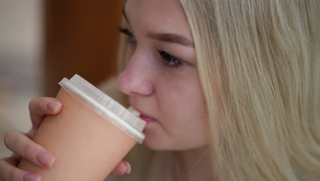 primer plano de una joven enfocada mientras bebe café, mirando pensativamente a algo en la distancia, capturado con un claro enfoque en su expresión y taza de café