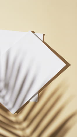 vertical video of shadow of plant over books with blank pages and copy space on yellow background