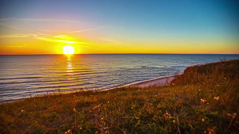 puesta de sol dorada en el horizonte del océano con suaves olas en la playa - lapso de tiempo