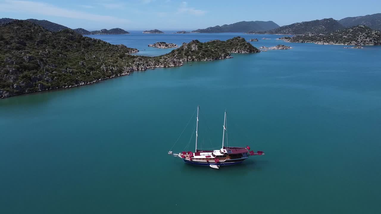 터키의 아페라라이 고대 도시에서 차분한 파란 물과 함께 만 한가운데에 고정 된 항해 보트의 공중 사진