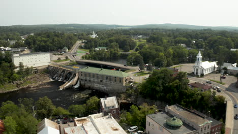 aerial footage of skowhegan, maine island downtown with kennebec river hydroelectric dam and church in the foreground