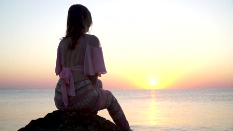 Mädchen-Sitzt-Auf-Dem-Felsen-Bei-Sonnenaufgang-Am-Meer