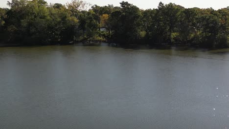 An-aerial-shot-above-a-park-with-a-pond-on-a-sunny-day