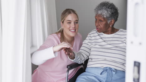 una enfermera caucásica sonriente hablando con una anciana afroamericana paciente, cámara lenta