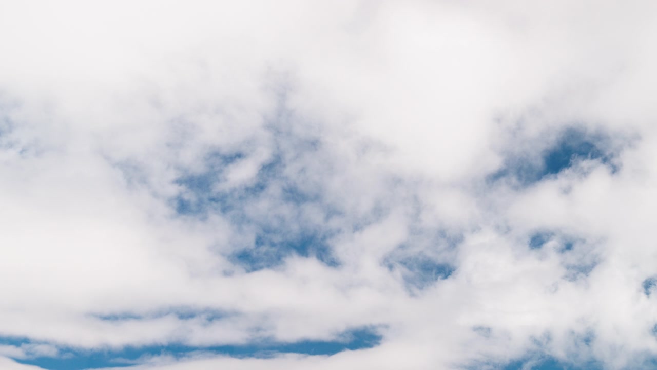 Soft white clouds drifting across a blue sky, creating a calm and natural atmospheric background. Ideal for time passing, weather visuals, overlays, and clean sky backgrounds.
