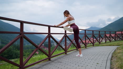 mujer estirándose al aire libre en un paisaje montañoso