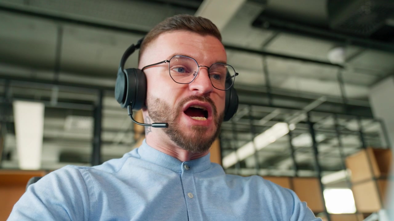 Ung man med headset som talar under ett online videosamtal på kontoret
