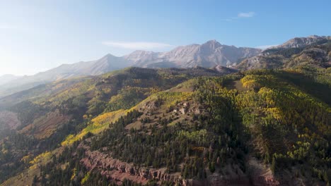 un avión no tripulado volando alto, girando lentamente, sobre los picos de las montañas rocosas, cerca de telluride, colorado, en un día soleado en la temporada de otoño