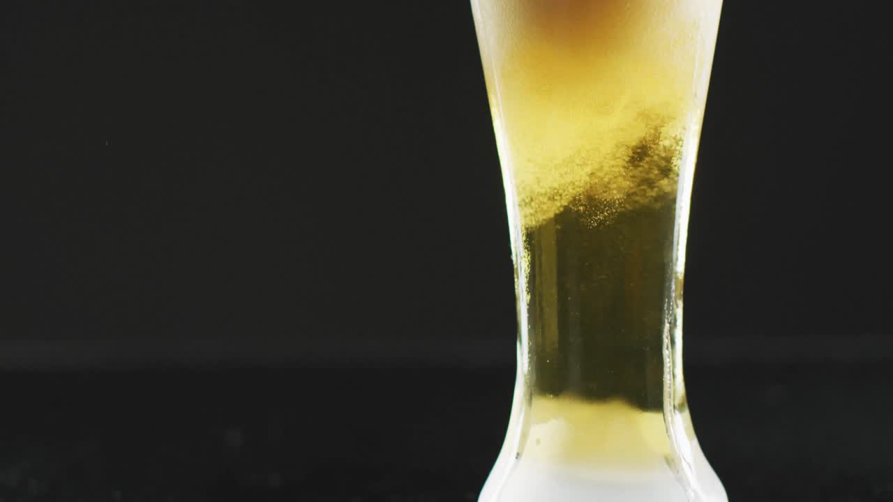 video de un vaso de cerveza con espuma sobre un fondo negro