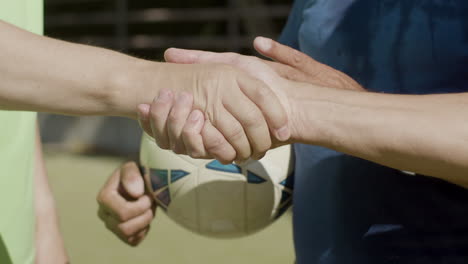 close up of two unrecognizable senior football players shaking hands before soccer match