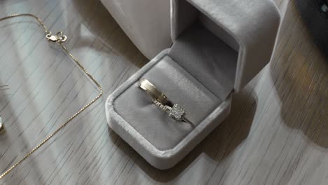 wedding rings shining in the sunlight inside a small box on a wooden table with glass