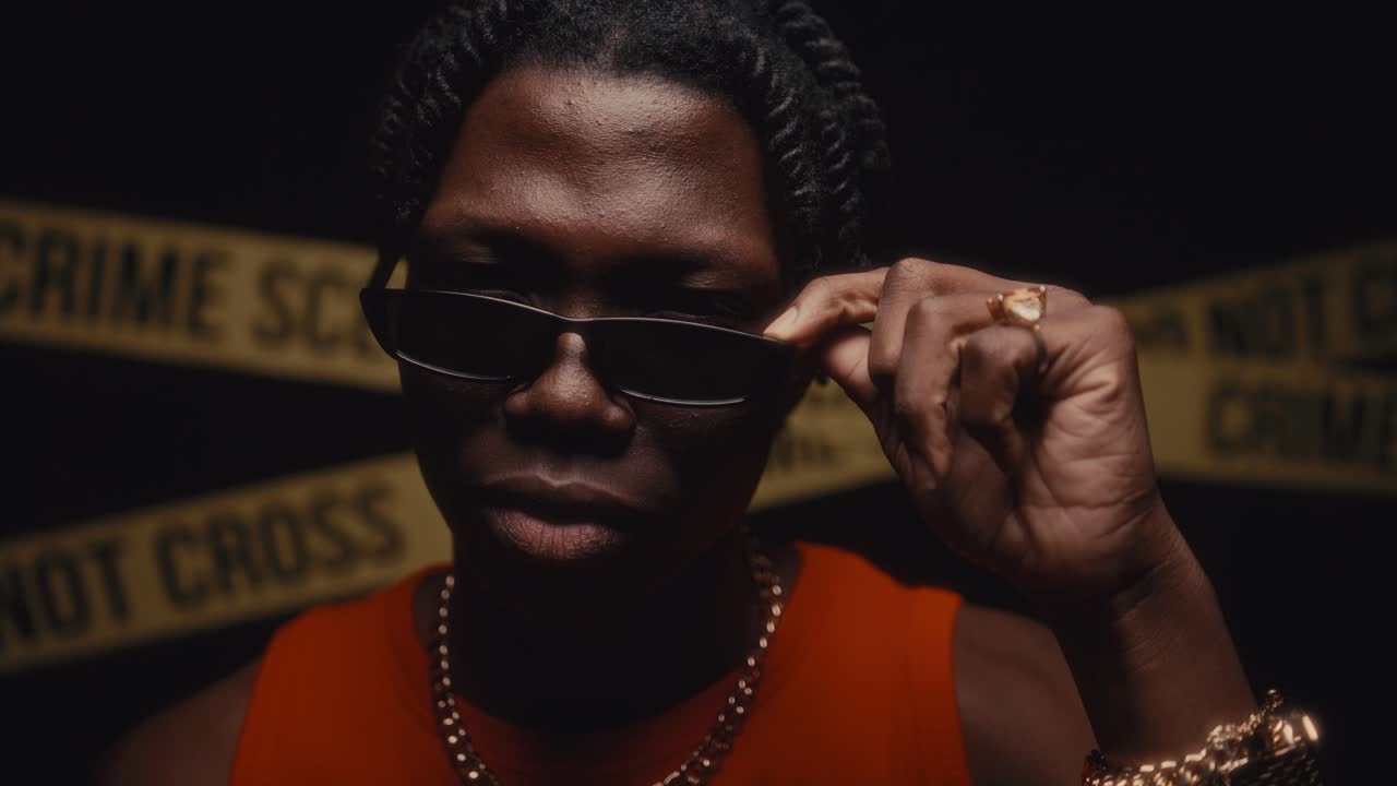 Portrait of Black Man in Sunglasses Looking Seriously into Camera at Crime Scene