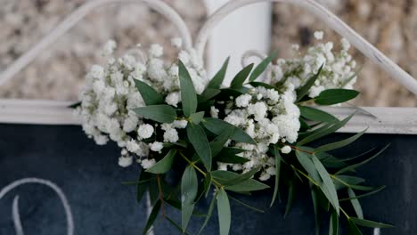 white baby’s breath and green leaves arranged on vintage white metal frame