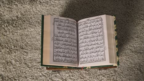 Overhead-Shot-Of-Open-Copy-Of-The-Quran-On-Stand-At-Home