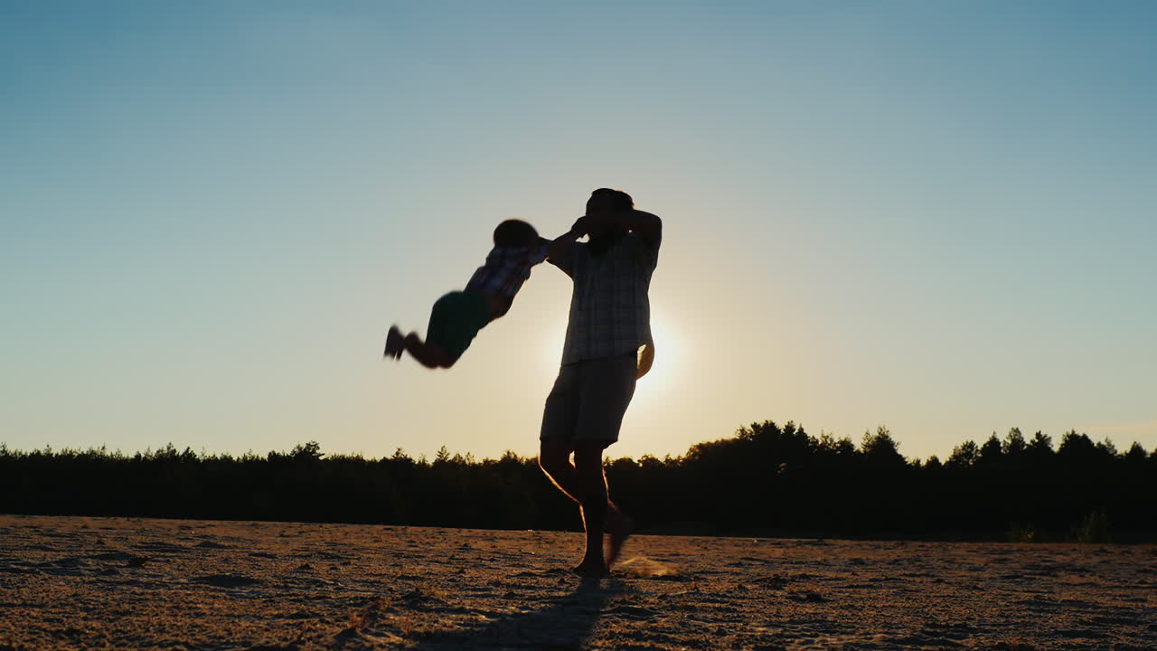 padre sano jugando con su hijo al atardecer - rodeándolo hermoso resplandor redondo del sol en th