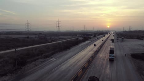 aerial view of traffic travelling on karachi to hyderabad motorway during sunset. follow shot