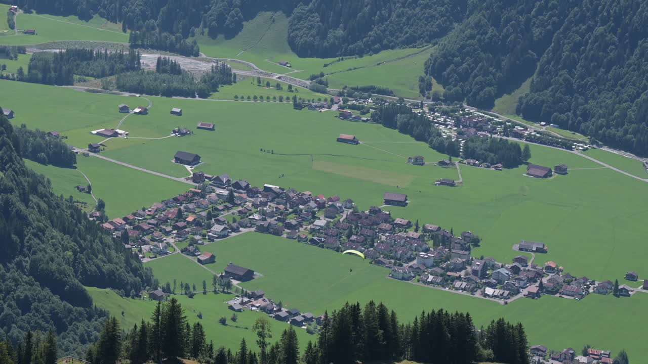 pueblo de engelberg en obwalden, pequeño pueblo cerca de verdes prados y bosques de abetos, paracaídas sobre las casas, alpes suizos