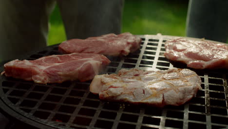 Manos-Del-Hombre-Poniendo-Rodajas-De-Carne-En-La-Parrilla-Al-Aire-Libre.-Chef-Preparando-Carne-En-El-Bosque