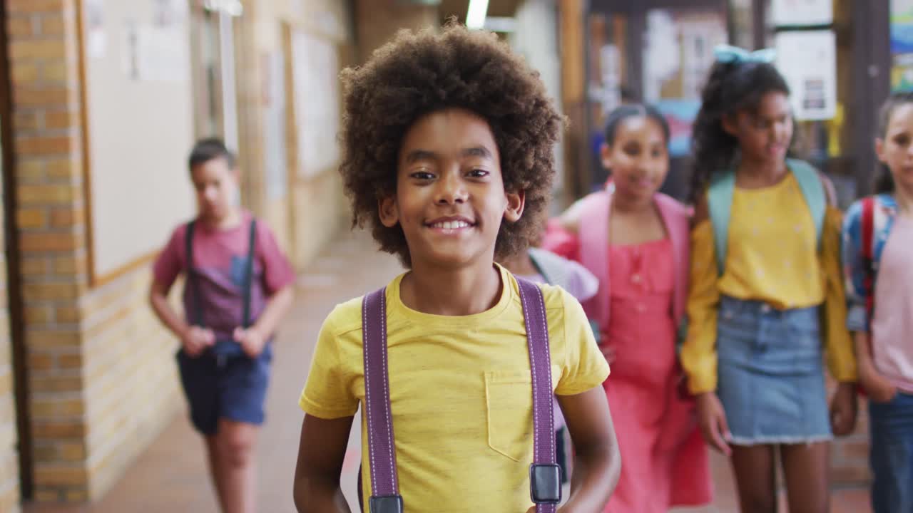 Portrait of happy african american schoolboy standing in corridor looking at camera