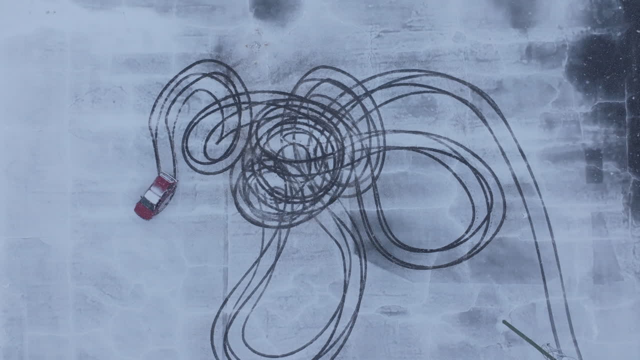Wide top down aerial footage of a suv doing donuts in a parking lot covered in snow in Chattanooga, TN.