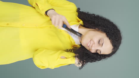 Vertical-video-of-Young-woman-combing-her-hair.