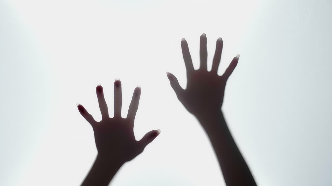 Silhouette of Hands Reaching Through Glass