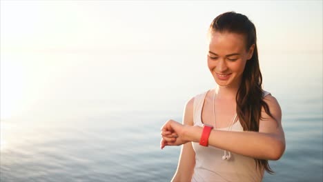 woman checking smartwatch by the lake at sunrise