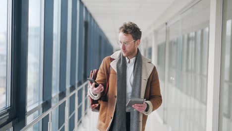 stylish adult man walking down the hall receives a joyful letter on a smartphone