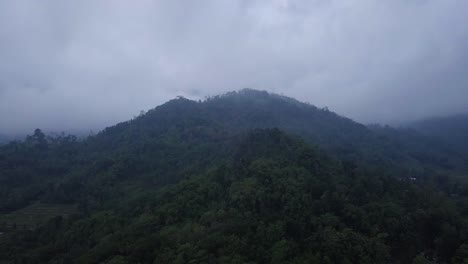 Vuelo-Aéreo-Hacia-El-Bosque-Y-La-Colina-Por-La-Mañana-Contra-Nubes-Oscuras-En-El-Cielo