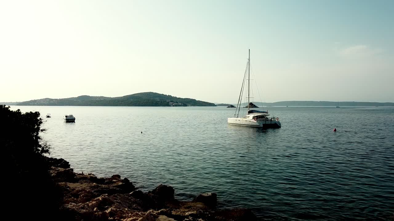 Carrellata aerea di un singolo catamarano ancorato in mare aperto vicino a isole distanti, Seget Vranjica Croazia