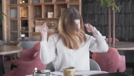hermosa chica está sentada en un café, poniendo música en su teléfono y bailando