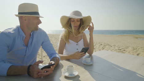 young couple using mobile phones on beach