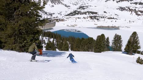 two young skiers showing short ski turns in a ski resort with beautiful mountain lake view in tyrol