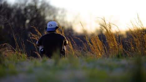 Niño-Sentado-En-La-Hierba-Durante-La-Puesta-De-Sol