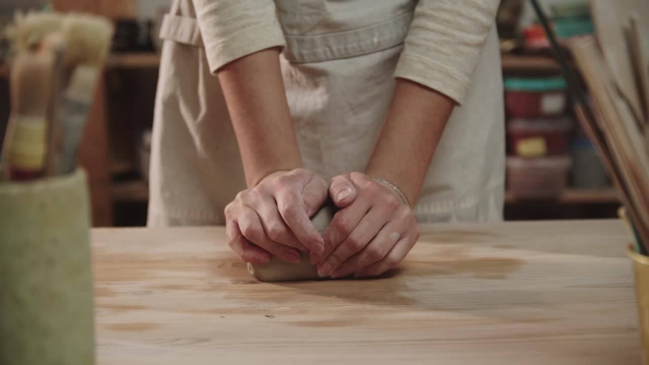 una alfarera amasa arcilla en la mesa en un estudio de arte