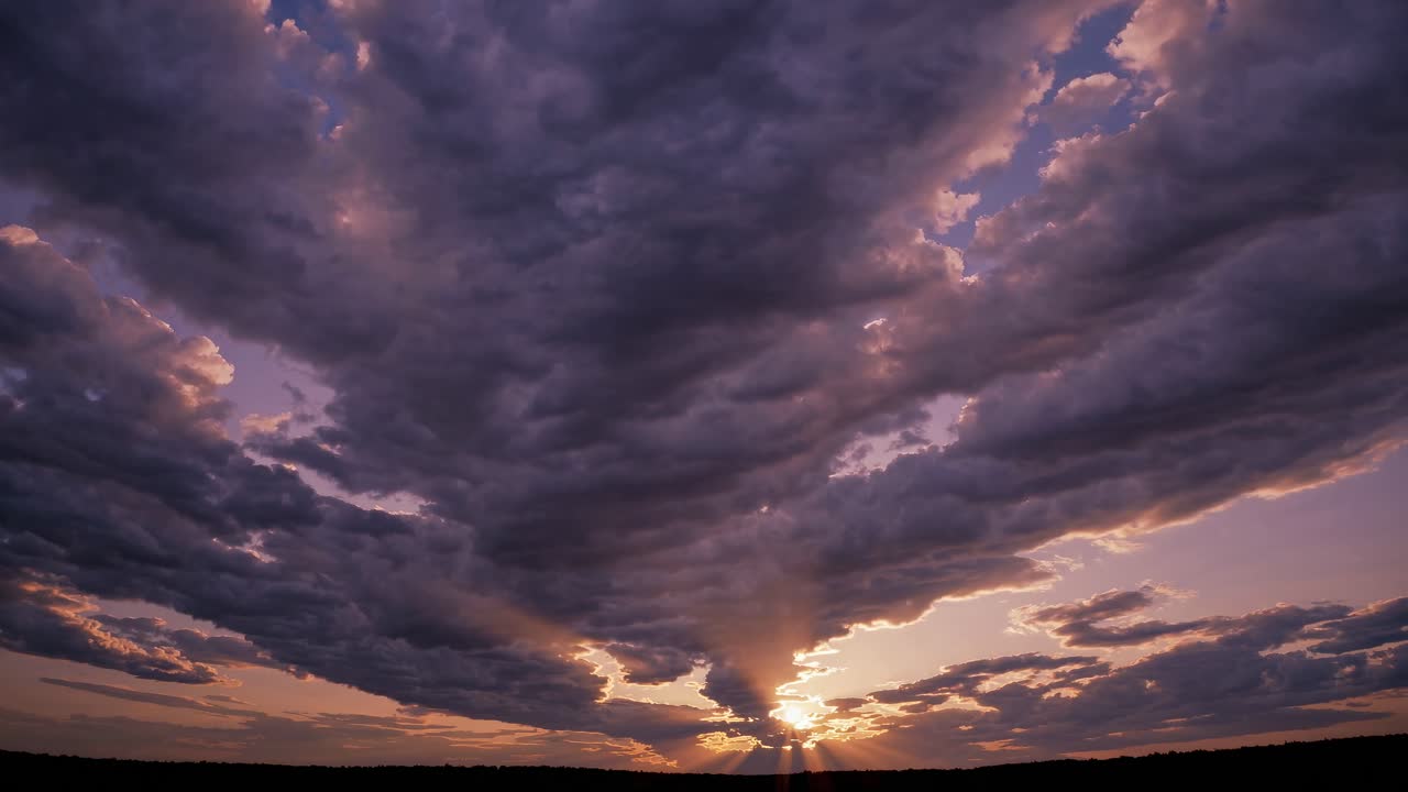 Dramatic sunset with sun rays piercing through thick clouds, captured from a low angle