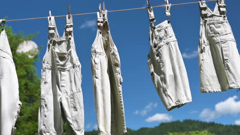 conjunto de ropa de mono colgada y seca en el tendedero con cielo azul de fondo durante el verano