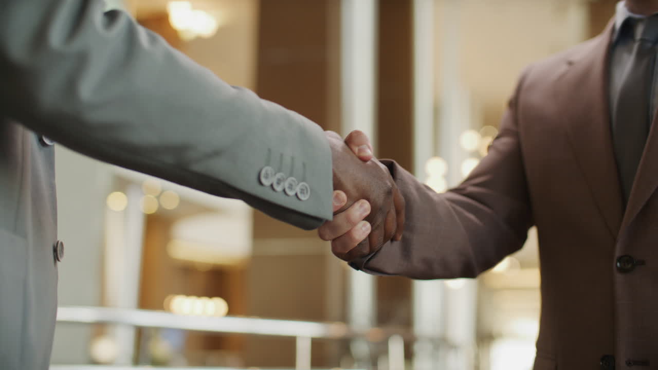 Close Up of Two Diverse Businessmen Shaking Hands in High-End Hotel Lobby