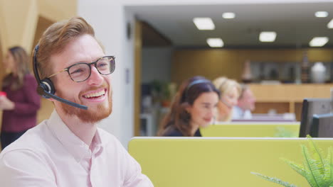 Businessman-Wearing-Phone-Headset-Talking-To-Caller-In-Customer-Services-Centre