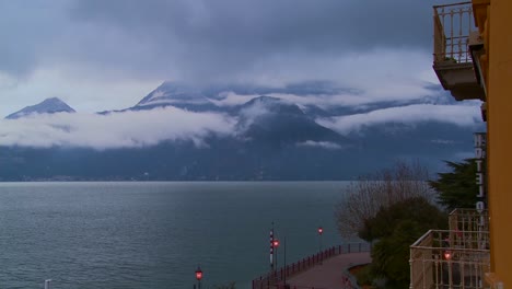 fog rolls in over the mountains of lake como italy with a hotel balcony naarby