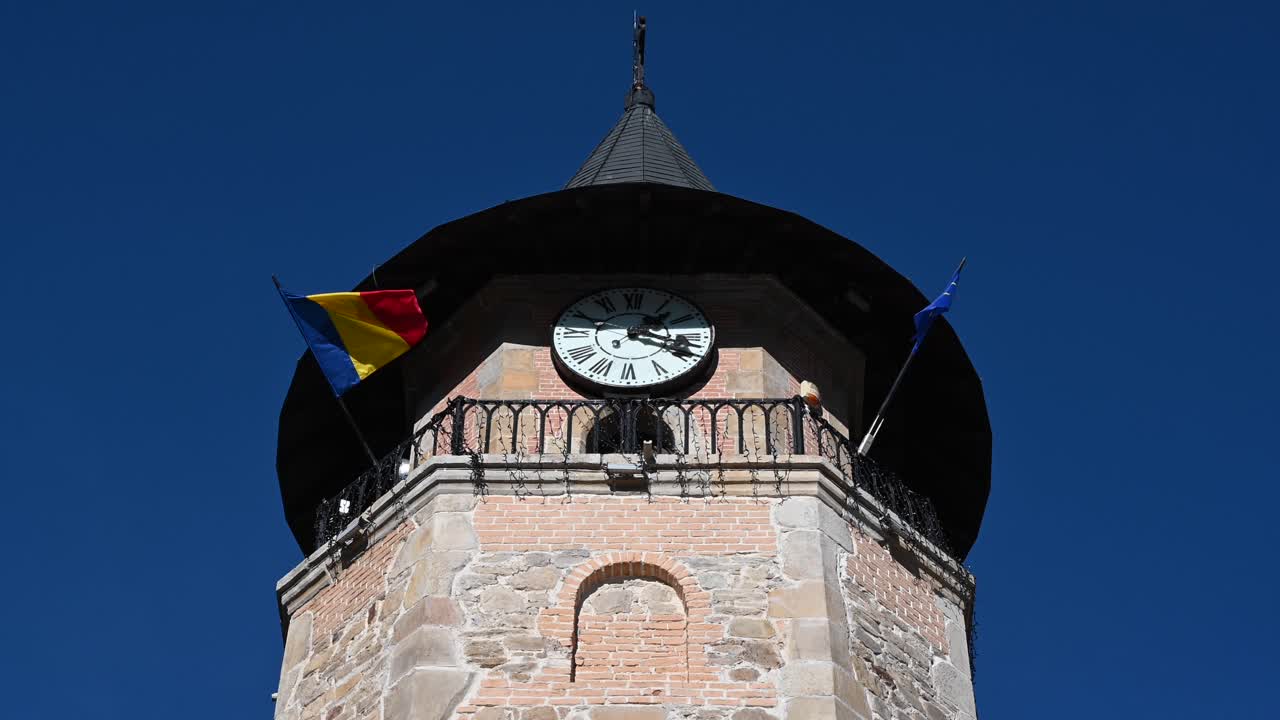 Close up of a Tower bell with the Romanian and European Union flags in Piatra Neamt, Romania on a blue sky background