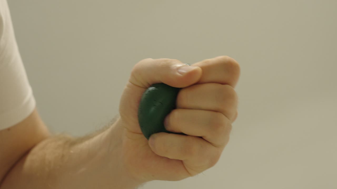 A hand squeezes a green stress ball to calm down and release tension — symbol of relaxation and stress relief