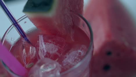 pedazo de sandía rosa se encuentra al lado del vaso con bebida fría