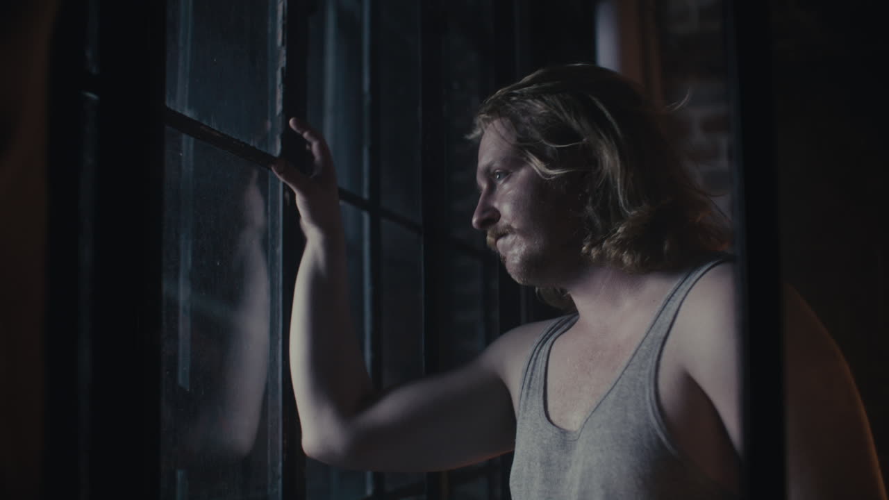 hombre mirando por una ventana por la noche