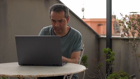 Adult-man-teleworking-from-home-on-his-terrace