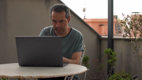 hombre adulto teletrabajando desde casa en su terraza