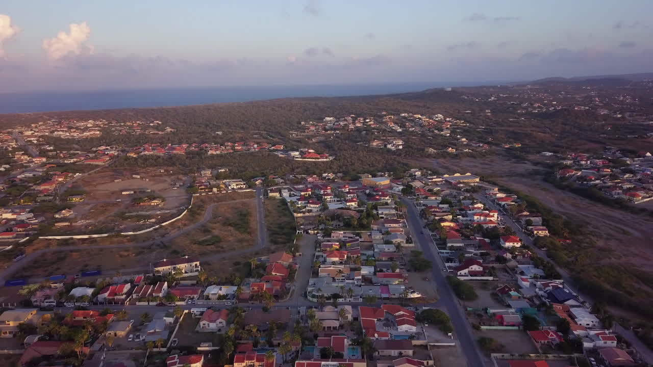 casas iluminadas por una hermosa puesta de sol en noord, aruba cerca de palm beach con el mar azul en el fondo